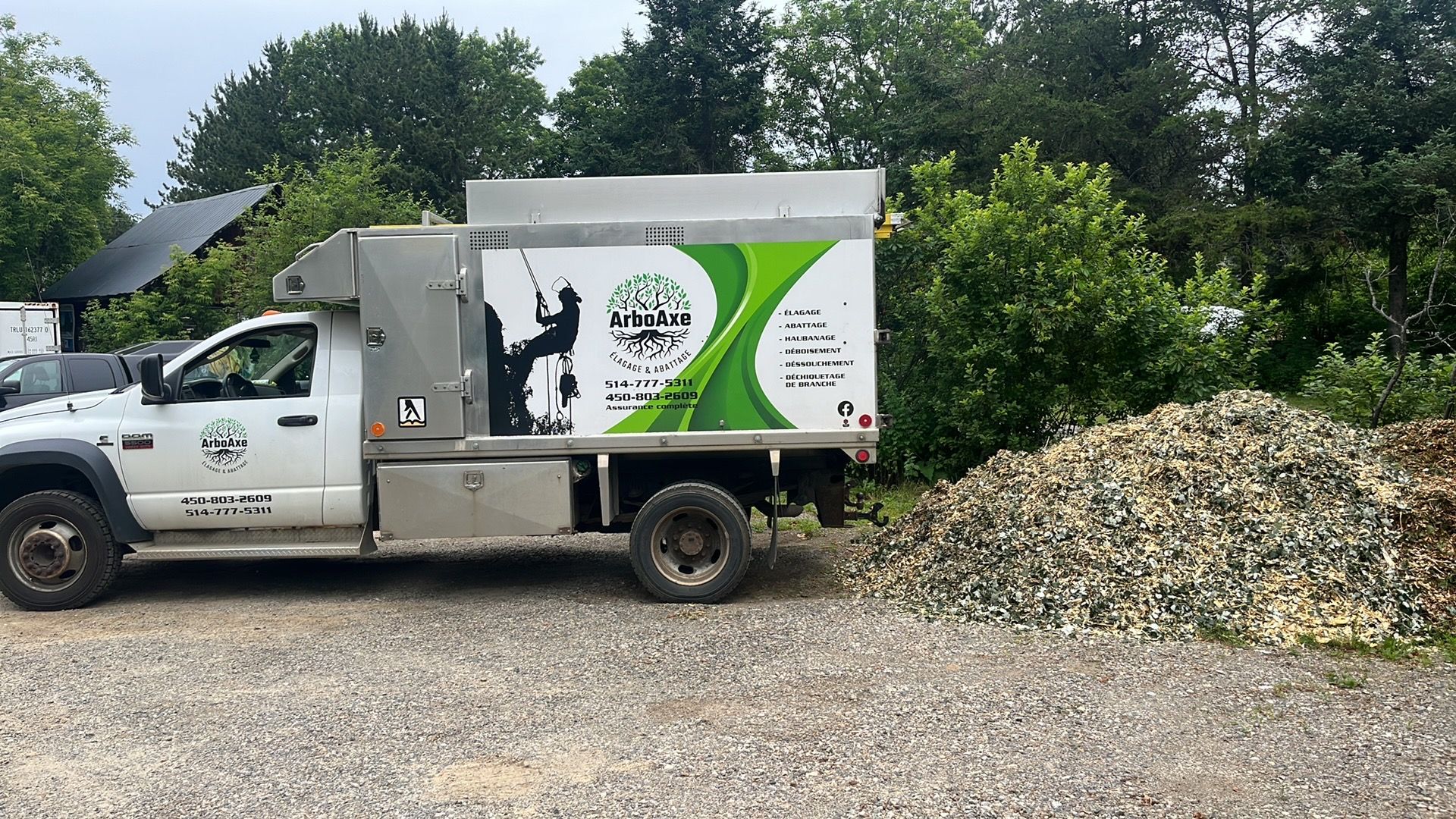 Camion d'élagage ArboAxe près d'un tas de copeaux.