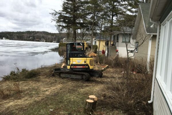 Excavatrice près d'une maison au bord d'un lac.