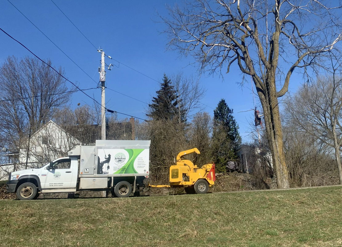 Camion et broyeur d'arbres près d'une maison.